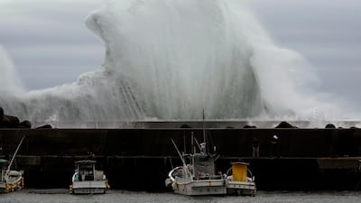 Men look at fishing boats as surging waves hit against the breakwater in town of Kiho, Mie Prefecture. AP