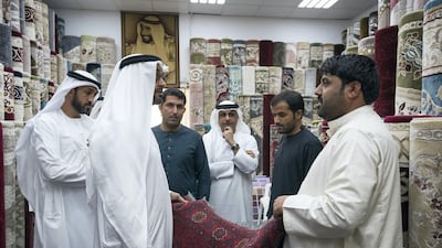 Sheikh Mohammed bin Zayed looks at a carpet at the Al Safa Carpet shop, in the carpet market of the Mina Zayed Port. Seen with Mohammed Al Mazrouei, Undersecretary of the Crown Prince Court of Abu Dhabi (back L), and Jassem Al Zaabi, Chairman of Abu Dhabi Executive Office and Abu Dhabi Executive Council Member (back C). Ryan Carter for the Crown Prince Court - Abu Dhabi