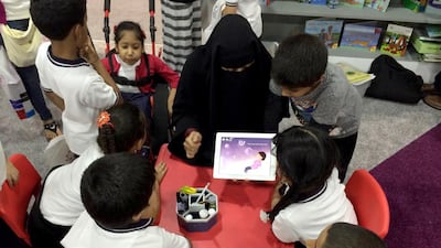 The author Maitha Al Khayat shows her reading app to children. Courtesy twofour54