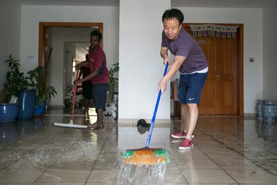 Yoon Shik Ahn, a resident from the Green Community, trying to get rid of water in his house. Mona Al Marzooqi/ The National
