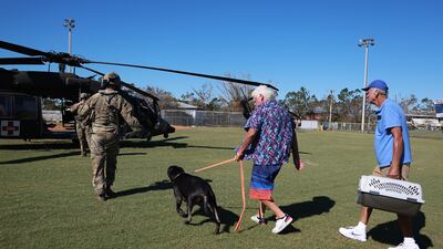 Tom O'Sullivan his dog Jack, and Harry Marquard prepare to be flown off the island in a Florida Army National Guard helicopter. Getty / AFP
