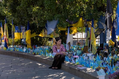 A woman sits by a makeshift memorial for Ukrainian and foreign fighters at Independence Square in Kyiv. AFP