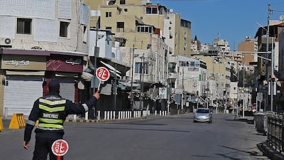A police officer holds up a stop sign as a car approaches in an almost-deserted street in Jordan's capital Amman, during a coronavirus lockdown. AFP