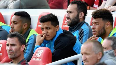 Alexis Sanchez, centre, looks on from the bench after being substituted during Arsenal's 4-0 defeat at Liverpool. The Chilean could be joining Chelsea-bound Alex Oxlade-Chamberlain, right, in departing Arsenal this summer, with Manchester City keen to take him to the Etihad Stadium. Michael Regan / Getty Images