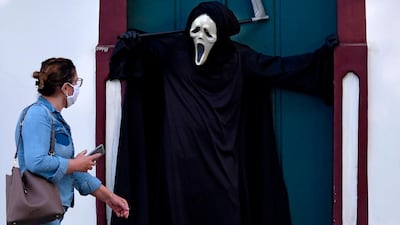 A woman looks at Brazilian actor Fabio de Almeida disguised as death to raise awareness of the importance of wearing face masks and social distancing to prevent the spread of the new coronavirus in Formiga, Minas Gerais state, Brazil. AFP