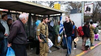 Israelis at the bus stop in Jerusalem that was the scene of Wednesday's bombing attack. The young man with the Israeli flag is demonstrating with a group of scouts in favour of non-violence and non-escalation of events between Israelis and Palestinians.