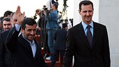 Mahmoud Ahmadinejad, the Iranian president, left, waves for photographers as he walks with Bashar Assad, the Syrian president, upon his arrival at al-Shaab presidential palace in Damascus yesterday.