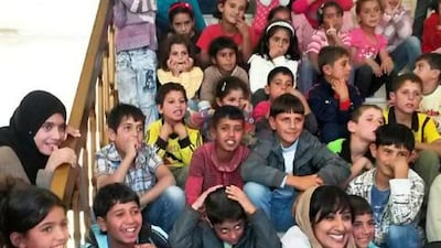Muna Harib sitting among Syrian refugee children in May. Ms Harib will be leading a team of 14 people, including five Emiratis, to hand out aid to Syrian refugees. Courtesy Muna Harib