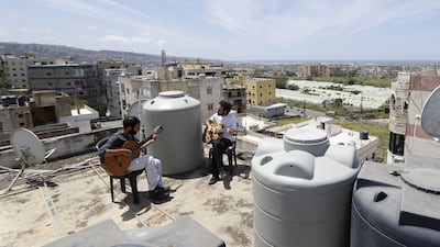 Lebanese Musician Ziad al-Zayyat (L) and his flatmate, interior designer Saad Molaeb, play their guitars on the rooftop of their building, during a lockdown imposed by the authorities in the town of Hadath, north of the capital Beirut on May 4. Usually the kingdom of water tanks and satellite dishes, Lebanon's roofs have recently been graced by unlikely scenes of confined residents fleeing their flats for space and fresh air. Joseph Eid/ AFP