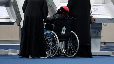 A woman in a wheelchair is helped to cast her vote on a terminal at Adnec on Tuesday
