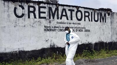 A medical staff member wearing a protective suit walks past the crematorium where victims of Ebola are burnt, in Monrovia. Pascal Guyot / AFP