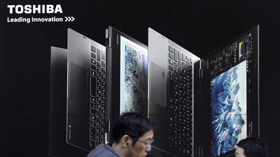 Pedestrians walk past an advertisement for Toshiba Corp.'s Dynabook laptop computer outside an electronics store in Tokyo, Japan, on Monday, Jan. 23, 2017. Bloomberg