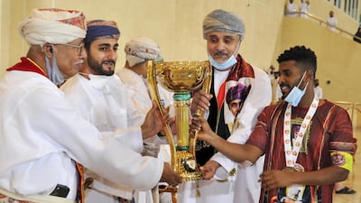 Dhi Yazan bin Haitham presents the trophy to Dhofar players after winning the Sultan Qaboos Cup final. AFP