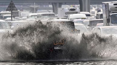 Vehicles try to navigate a flooded road in Dubai on Thursday. AFP