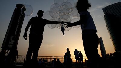 A balloon vendor sells light balloons while people watch fireworks over the sky of Dubai Festival City (DFC) on the second day of Eid Al-Fitr in UAE. EPA