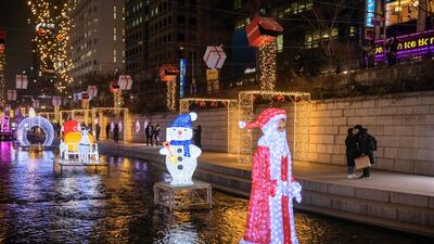 A couple kiss behind a Christmas-themed light display at along the Chongye stream in central Seoul. AFP