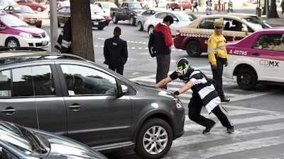 A man who calls himself 'Peatonito' and dresses as a wrestler, pushes a car as he performs his routine in the streets of Mexico City on April 21, 2015. Peatonito is a character who resembles a superhero trying to raise drivers' awareness so thay they respect crosswalks on the streets of Mexico City. Yuri Cortez/AFP Photo