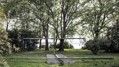 In a grassy clearing in a wooded garden on the island of San Giorgio Maggiore in the Venetian Lagoon, an odd structure in stainless steel spreads out in straight lines.