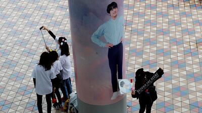 Fans take photos in front of a wall photo of a member of South Korean boy band BTS outside Tokyo Dome. Kim Kyung-Hoon / Reuters