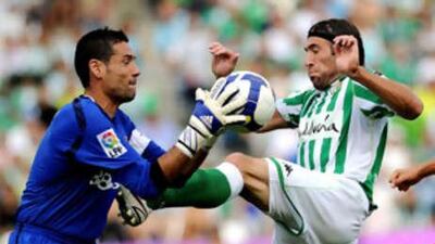 Sevilla's keeper Andres Palop grabs the ball off the toes of the Betis striker Mariano Pavone.