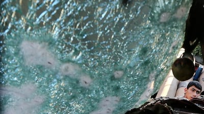 A Palestinian man can be seen through the damaged window of a vehicle as he inspects the scene of an air strike on a garage in Al Zeitoun district, northern Gaza, on May 5, 2016. Mohammed Salem/Reuters