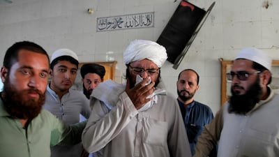 People comfort a cleric who mourns over lost of his students at the site of a bomb explosion in an Islamic seminary, in Peshawar, Pakistan. AP Photo