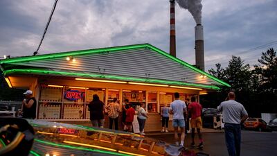 People line up for ice cream at Glens Custard in the shadow of GenOns Cheswick Power Station in Pennsylvania which still burns coal to produce 637MW of electricity for the region. Spending on renewables fell 8% last year, according to the IEA, which expects a rebound in 2021. Getty Images/AFP