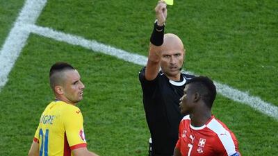 Russian referee Sergei Karasev (C) shows a yellow card to Switzerland’s forward Breel Embolo for a foul on Romania’s defender Dragos Grigore during the Euro 2016 group A football match between Romania and Switzerland at the Parc des Princes stadium in Paris on June 15, 2016. / AFP / LIONEL BONAVENTURE