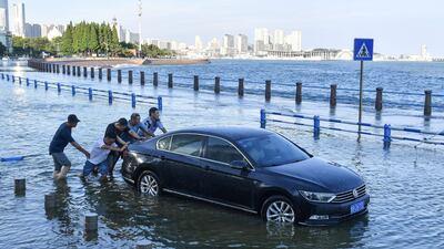 People push a car on a flooded street as waves caused by Typhoon In-Fa surge over a barrier along the coast in Qingdao in China's eastern Shandong province.