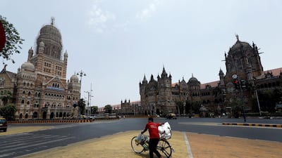 A man walks pushes his bicycle in front of the Brihanmumbai Municipal Corporation building and the Chhatrapati Shivaji Maharaj Terminus during a weekend lockdown in Mumbai, India, on April 10, 2021. Reuters