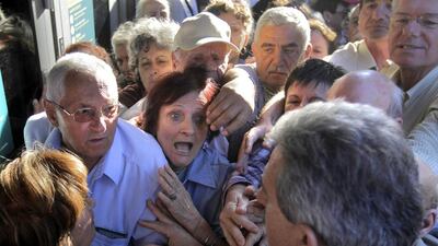 Pensioners who do not own ATM cards argue with a bank employee in Athens. Orestis Panagiotou / EPA