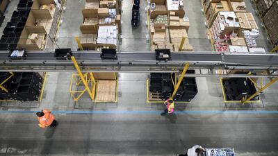 Workers prepare customer orders for dispatch as they work around goods stored inside an Amazon.co.uk fulfillment centre in Peterborough. AFP