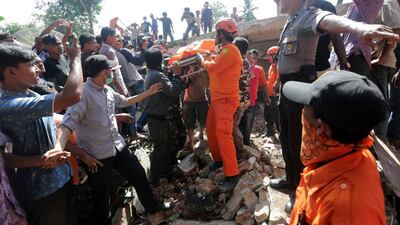 Rescue workers and police remove a victim from a collapsed building following an earthquake in Lueng Putu. Antara Foto / Irwansyah Putra / via Reuters