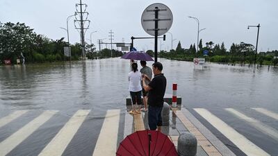 People look out at a flooded road in Yuyao.