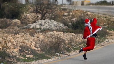A Palestinian demonstrator dressed as Santa Claus hurls stones towards Israeli troops during clashes at a protest against U.S. President Donald Trump's decision to recognize Jerusalem as the capital of Israel, near the West Bank city of Ramallah December 19, 2017. REUTERS/Mohamad Torokman TPX IMAGES OF THE DAY