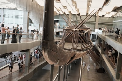 People take pictures of the solar boat of King Khufu, during the second day for visitors after the official opening of the Grand Egyptian Museum in Giza, Egypt. AP