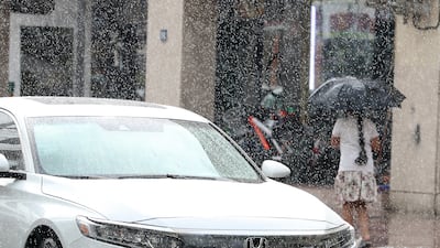 A girl holding umbrella to shelter from a downpour in the Al Karama area of Dubai. Pawan Singh / The National