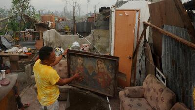 Typhoon survivor Francis Batula, 35, removes the mud from his Jesus and Mary portrait inside his destroyed houses in Palo, Tacloban. His aunt’s body was found but not those of her husband and daughter, and he refuses to acknowledge that his uncle and cousin are likely dead. Noel Celis / AFP