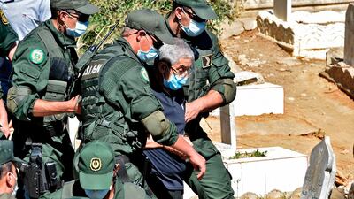 Former Algerian prime minister Ahmed Ouyahia, who is serving a 15-year prison sentence for corruption, is escorted by police after attending the funeral of his brother at a cemetery in the capital Algiers. AFP