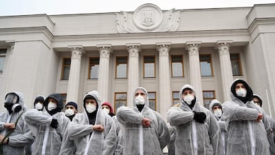 Activists of National Corps far-right party wearing gas masks and protective suits salute as they gather in front of Ukraine’s parliament. AFP