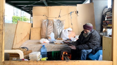 Mohammed Maghrabi warms himself under the bridge before the fire that devastated his shelter.