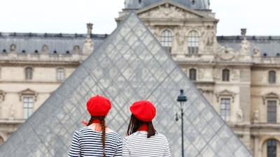 Tourists wearing red berets stand in front of the glass Pyramid of the Louvre museum in Paris. Reuters