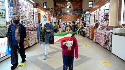 A girl waves the Kuwaiti flag at Kuwait City's Souk Al Mubarakiya. Events to mark National Day and Liberation Day on February 25 and 26 have been cancelled due to the coronavirus pandemic. EPA