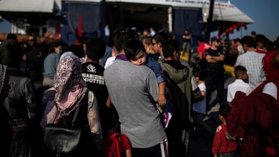 A migrant from Afghanistan carries his son as they prepare to board a ship that will transfer them from Lesbos to the mainland. REUTERS