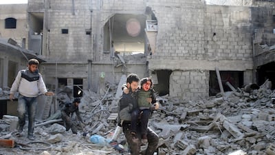A man carries an injured boy as he walks on the rubble of damaged buildings in the rebel held besieged town of Hamouriyeh, eastern Ghouta, near Damascus, Syria. Bassam Khabieh / Reuters
