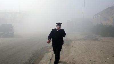 An Egyptian policeman walks amid smoke rising from a fire at a textile factory in Obour industrial district, outskirts of Cairo, Egypt. At least 20 people died and 24 were injured after a fire broke out in a textile factory northeast of Cairo, local authorities reported after controlling the fire. EPA