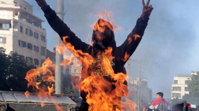 An anti-government protester shouts slogans in front of a fire set by demonstrators to block the main highway that link east and west Beirut. AP