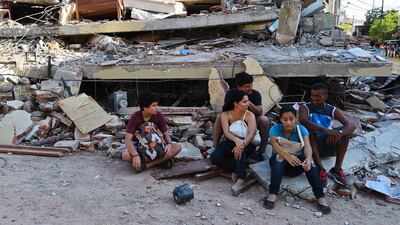People rest in front of a destroyed house in Manta, Ecuador. Luis Acosta / AFP Photo