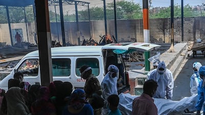 Relatives mourn as ambulance staff wearing Personal Protective Equipment carry the body of a Covid-19 coronavirus victim for a funeral at a crematorium in New Delhi. AFP