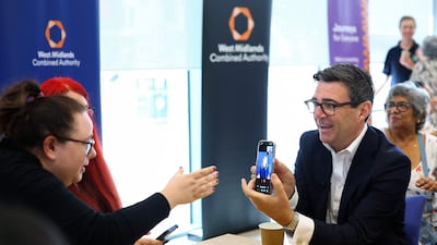 Prime Minister Andy Burnham uses a British Sign Language interpreter on a smartphone during a visit to Wolverhampton Bus Station. AFP